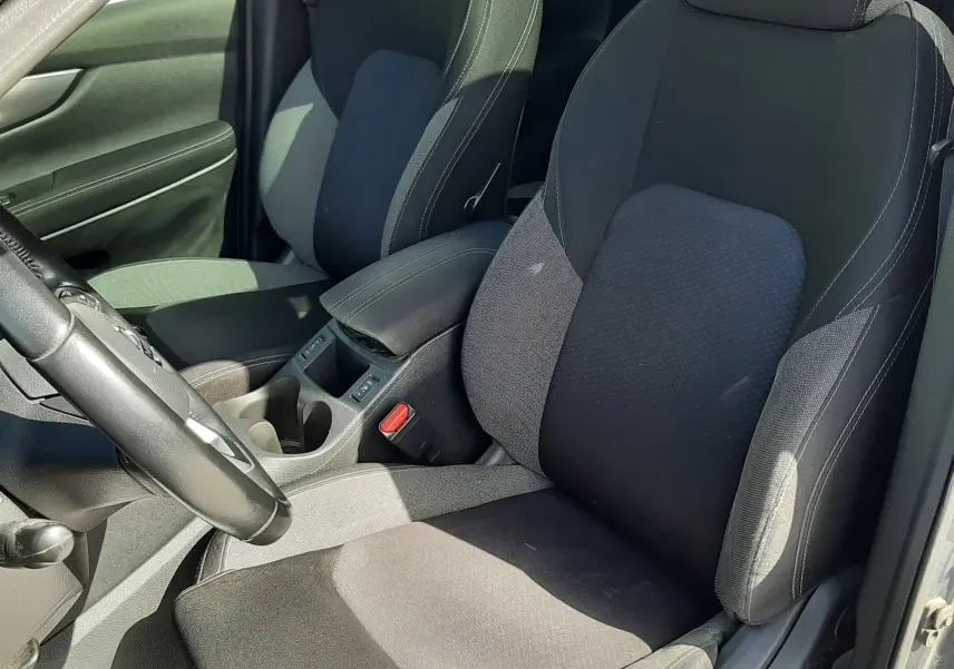 Vue rapprochée de l’intérieur du Nissan Qashqai 2018, sièges avant en tissu gris noir avec accoudoir central.