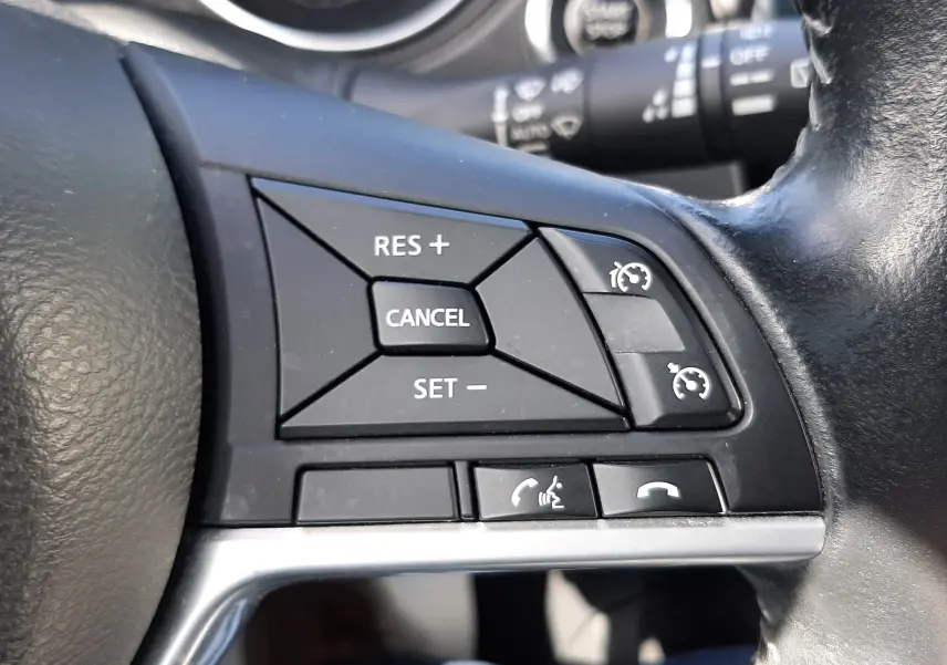 Gros plan sur les commandes de régulateur de vitesse et téléphone au volant noir du Nissan Qashqai 2018.