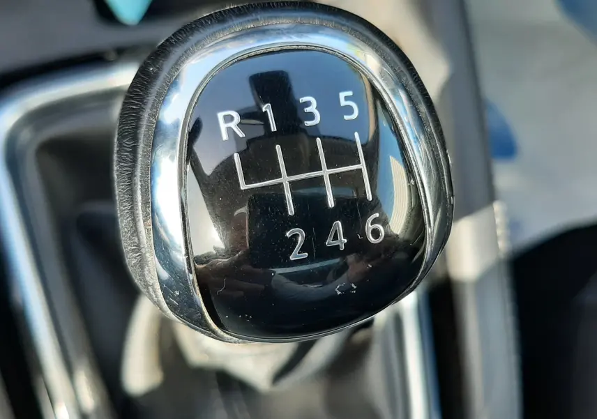 Gros plan sur le levier de vitesses manuel noir brillant du Nissan Qashqai 1.2 DIG-T 115CH N-Connecta, intérieur gris-noir.