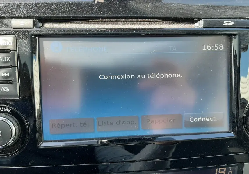 Écran tactile central du Nissan Qashqai 2018 montrant la connexion au téléphone, avec commandes climatisation en dessous.