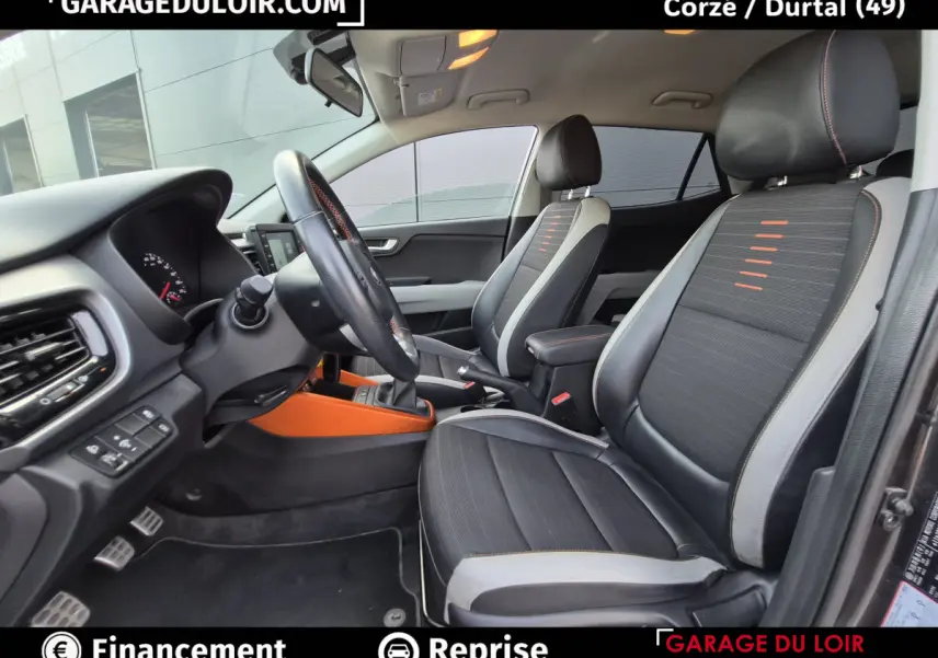 Vue intérieure côté conducteur de la Kia Stonic 1.0 T-GDi 2019 avec sièges noirs et détails orange sur console centrale.