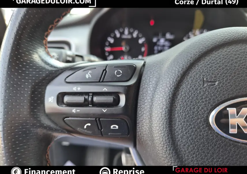 Gros plan sur les commandes du volant en cuir noir perforé d’un KIA STONIC 1.0 T-GDi 2019, côté gauche.