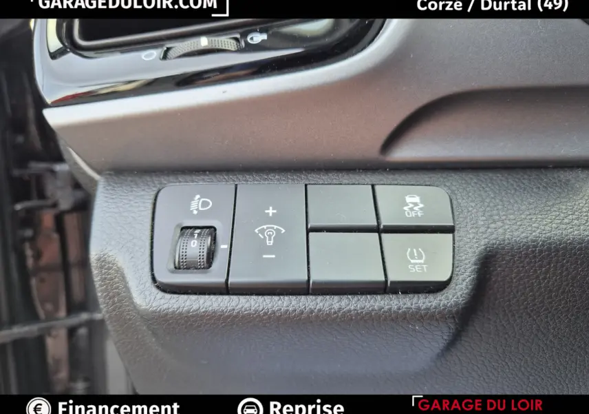 Gros plan sur les commandes de réglage des phares et du contrôle de traction d’une KIA STONIC 1.0 T-GDi 2019, intérieur noir.