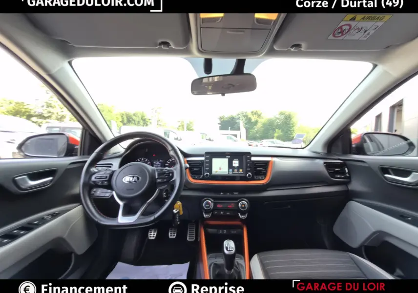 Vue intérieure avant du Kia Stonic 2019, tableau de bord noir avec inserts orange et volant multifonctions cuir.