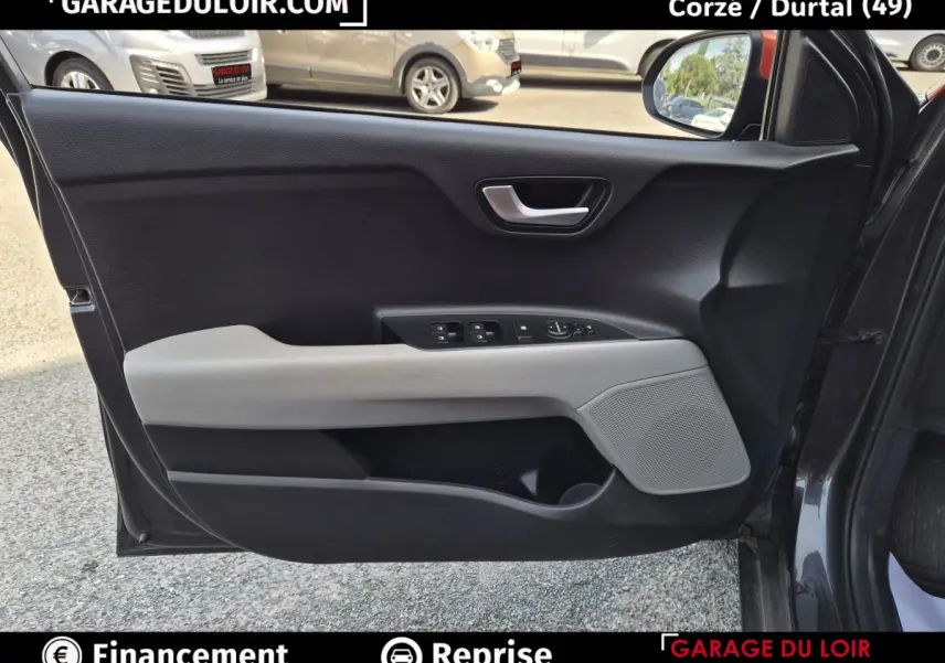Vue intérieure côté gauche de la porte avant d'une KIA STONIC 2019 avec garniture noire et beige et commandes électriques.