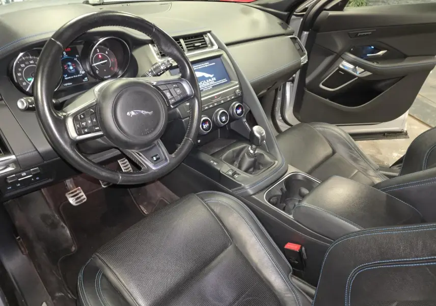 Vue intérieure côté conducteur de la Jaguar E-PACE D150 AWD R-Dynamic S 2019, sièges cuir noirs avec surpiqûres bleues.