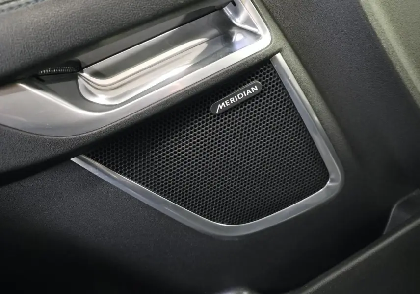Gros plan sur l'enceinte Meridian intégrée à la porte intérieure côté conducteur du Jaguar E-PACE gris 2019.