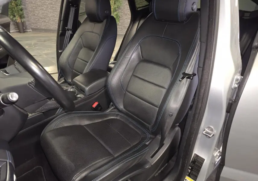 Vue intérieure côté conducteur des sièges sport en cuir noir avec surpiqûres bleues du Jaguar E-PACE gris 2019.