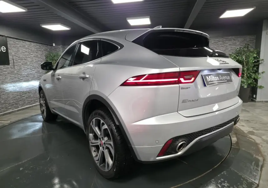 Jaguar E-PACE gris métallisé en 3/4 arrière droit, avec jantes 20 pouces et feux arrière LED distinctifs.