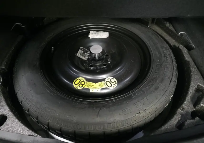 Gros plan sur la roue de secours noire de taille réduite dans le coffre du Jaguar E-PACE gris 2019.