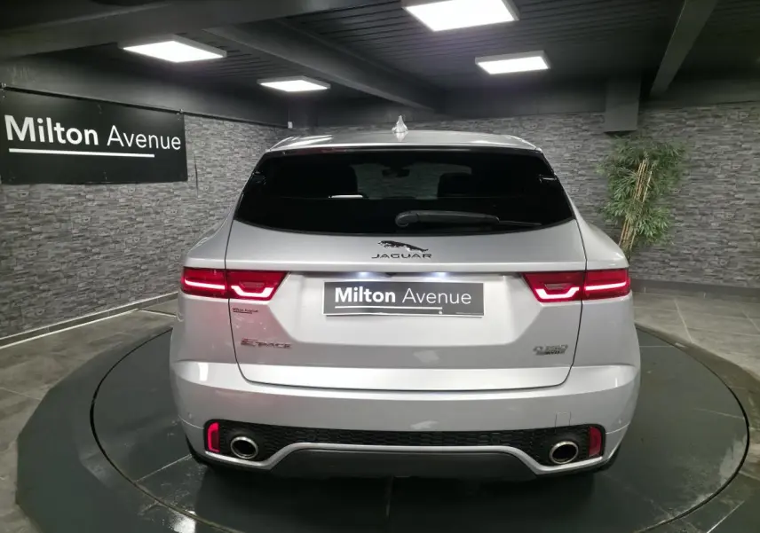 Vue arrière d'un Jaguar E-Pace gris métallisé 2019 avec feux LED et doubles sorties d'échappement visibles.