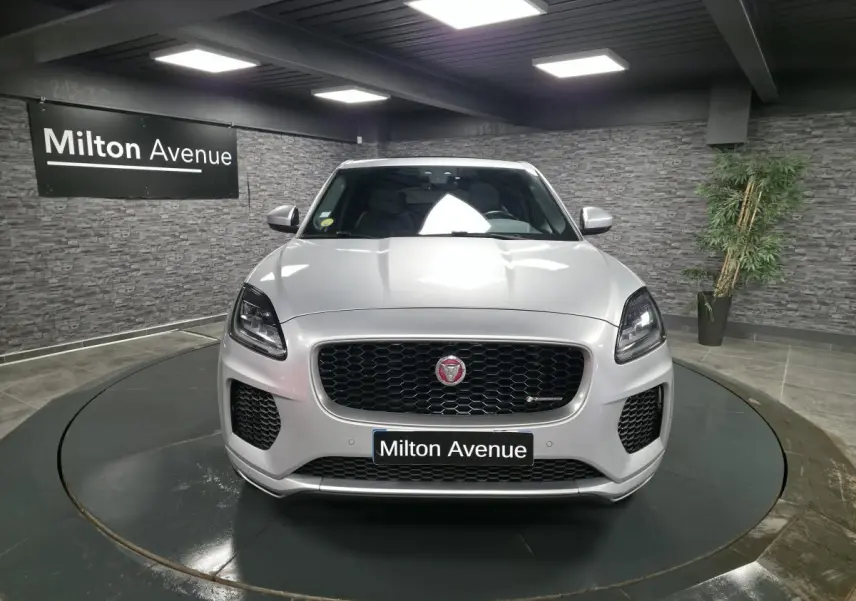 Jaguar E-PACE gris vue de face en intérieur, calandre noire avec logo Jaguar et phares LED marquants.
