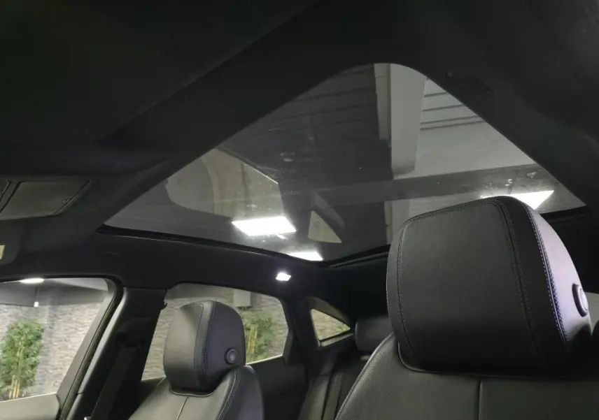 Intérieur du Jaguar E-PACE gris, vue sur les sièges avant en cuir noir et le toit panoramique fixe.