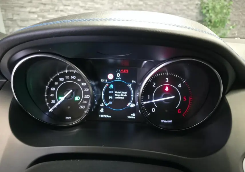 Vue rapprochée du tableau de bord noir du Jaguar E-PACE gris, affichant compteurs et écran digital central.