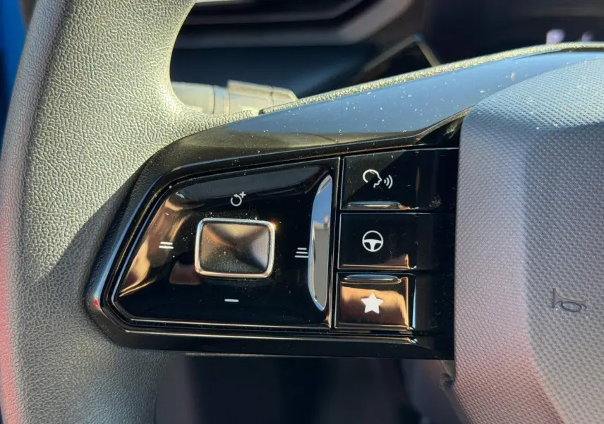 Gros plan sur les commandes multifonctions noires à gauche du volant gris clair du MG3 1.5 Hybrid+ 2024.
