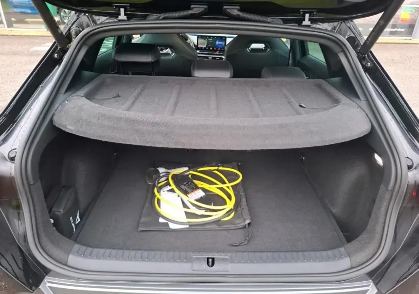 Coffre ouvert vu de l'arrière d'une CUPRA Formentor noir 1.4 E-HYBRID 245 VZ avec câble de recharge jaune visible.