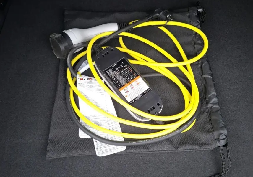 Câble de recharge jaune et noir posé dans le coffre d’un CUPRA Formentor 1.4 E-HYBRID 2023 noir.