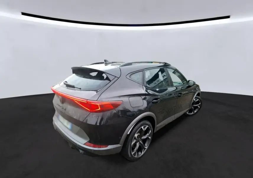 Vue 3/4 arrière droite d'une CUPRA Formentor 1.4 E-HYBRID 245 VZ noire avec feux arrière LED allumés.