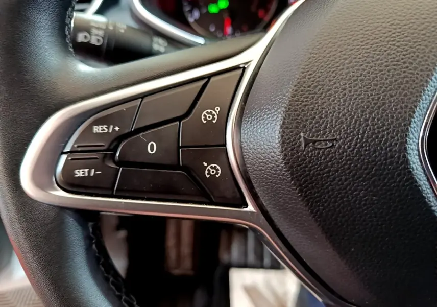 Gros plan sur le côté gauche du volant cuir synthétique noir de la Renault Clio Business TCe 100 2020 avec commandes de régulateur.