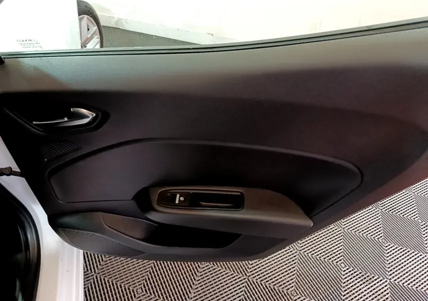 Vue intérieure côté gauche de la porte avant blanche d'une Renault Clio Business TCe 100 avec commande de vitre électrique.