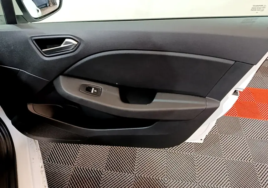 Vue intérieure côté gauche de la porte avant blanche d'une Renault Clio Business TCe 100, avec panneau noir et commande de vitre.