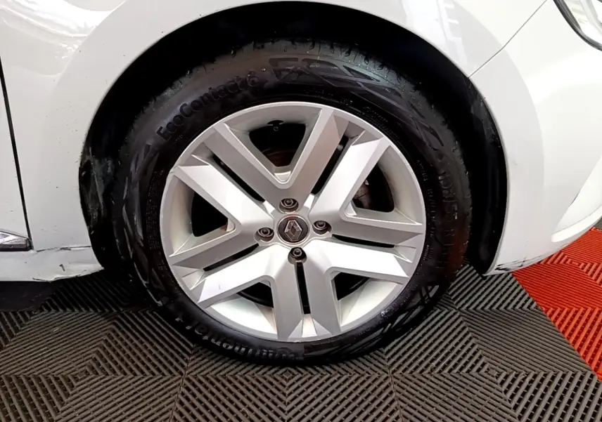 Gros plan sur la roue avant droite d'une Renault Clio blanche, mettant en valeur la jante alliage et le pneu Continental.