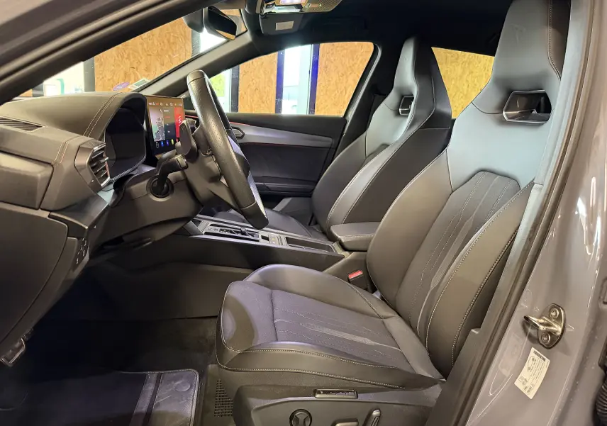 Vue intérieure côté conducteur du CUPRA Formentor gris 2023, mettant en valeur les sièges sport en cuir et tissu avec surpiqûres contrastées.