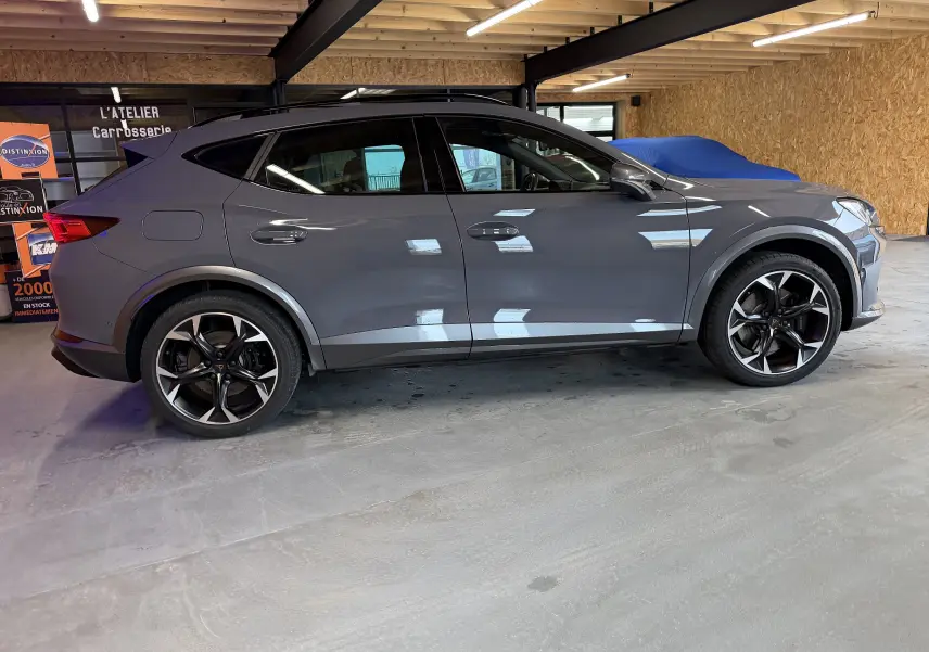 Vue de profil côté gauche d'un CUPRA Formentor gris 2023 hybride, avec jantes noires et détails sportifs en intérieur.