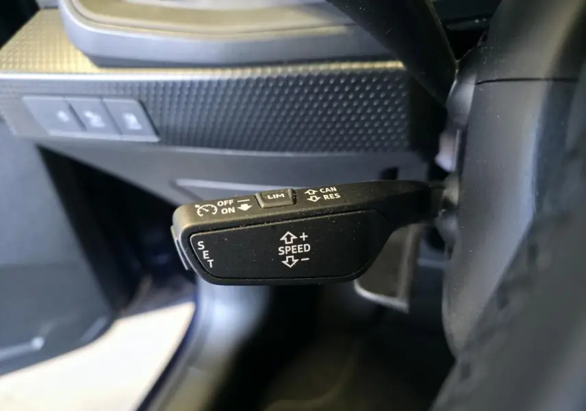 Gros plan sur le levier de régulateur de vitesse noir à gauche du volant dans l’Audi A1 Sportback 2024.