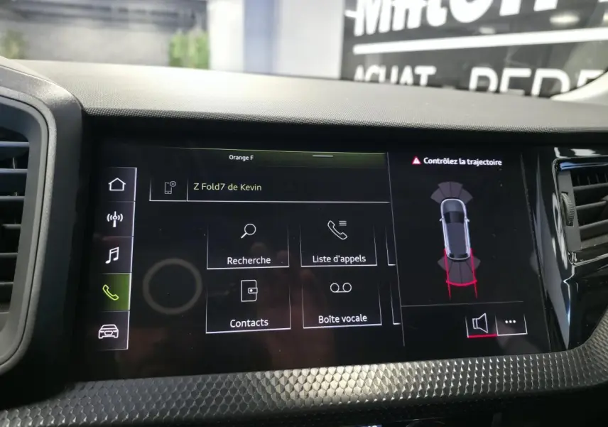 Écran tactile central de l’Audi A1 2024 affichant le menu appels et l’aide au stationnement, avec finition noire texturée.