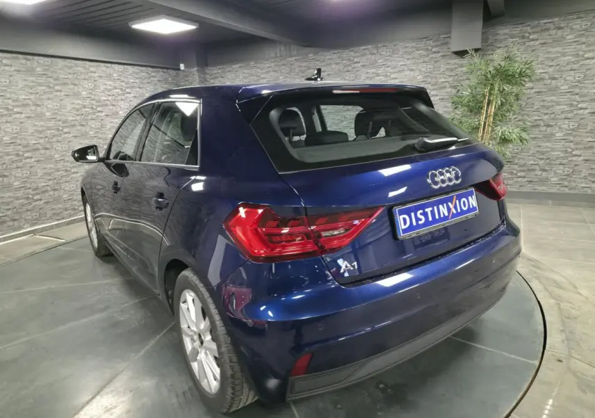 Audi A1 Sportback bleu métallisé vue 3/4 arrière droit, avec feux arrière LED et jantes aluminium 16 pouces.