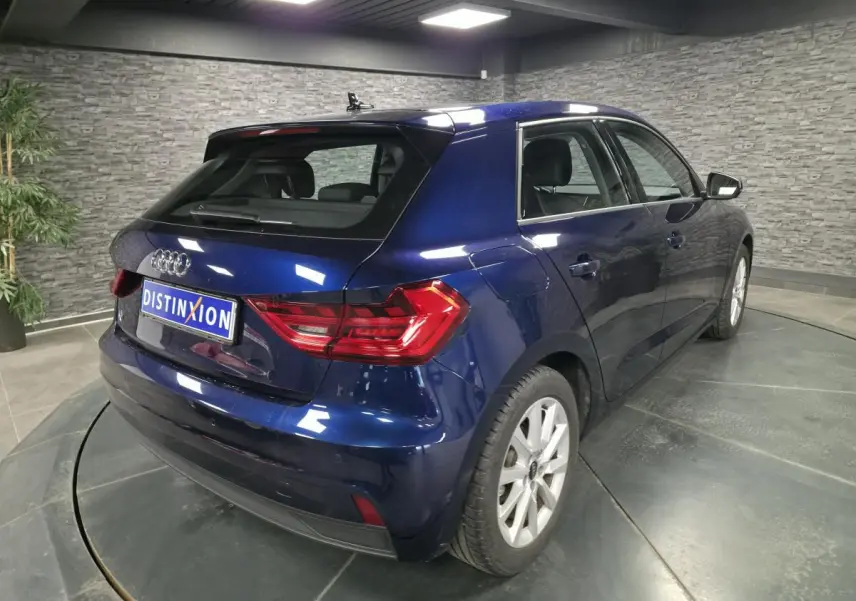 Audi A1 Sportback bleu métallisé vue 3/4 arrière droit en intérieur avec feux arrière LED et jantes 16 pouces.