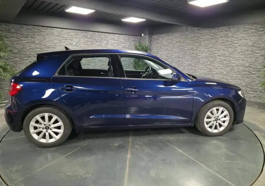 Audi A1 Sportback bleu métallisé vue de profil côté gauche dans un showroom avec jantes aluminium 16 pouces.