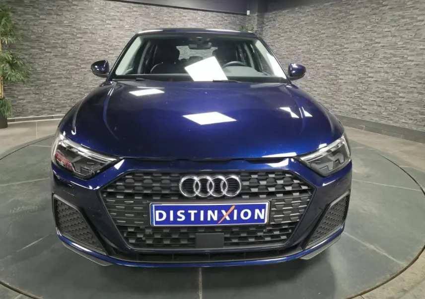 Vue avant d'une Audi A1 Sportback 2024 bleu métallisé avec calandre noire et phares LED distinctifs.