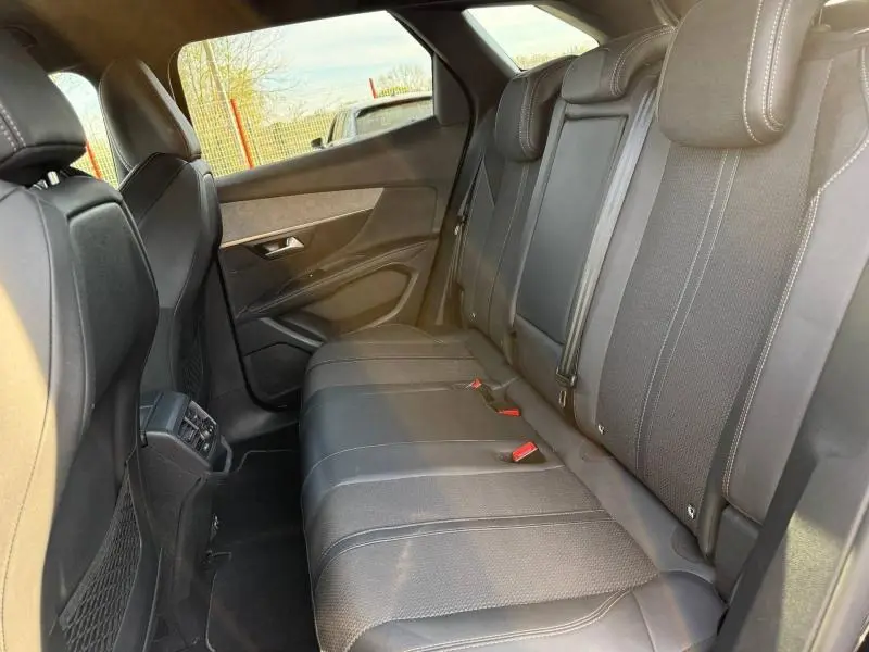 Vue intérieure arrière droite du Peugeot 3008 2024, sièges en cuir noir avec surpiqûres contrastantes et ceintures rouges.