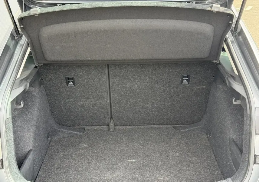 Coffre ouvert vu de l'arrière d'une Skoda Scala gris graphite, montrant l'espace de chargement vide et doublé de moquette.