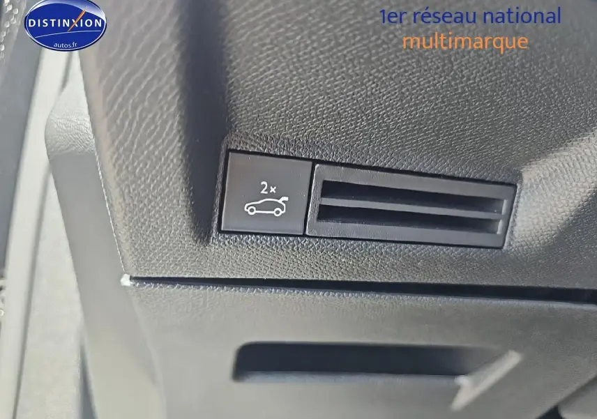 Gros plan sur le bouton d'ouverture du coffre dans l'habitacle noir du Peugeot 3008 1.2 hybrid 145 GT.