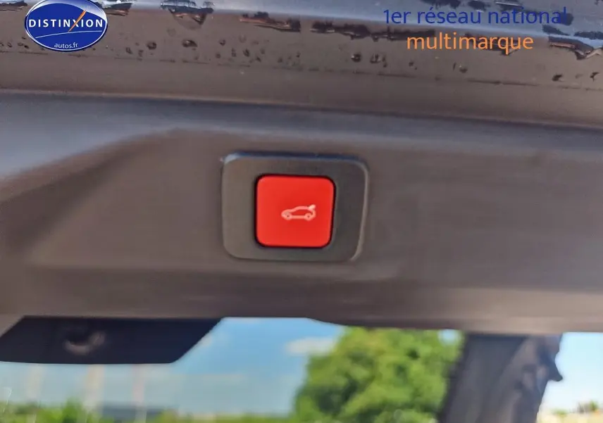 Bouton rouge d'ouverture électrique du coffre visible sous le hayon noir d'un Peugeot 3008 hybride 2025.