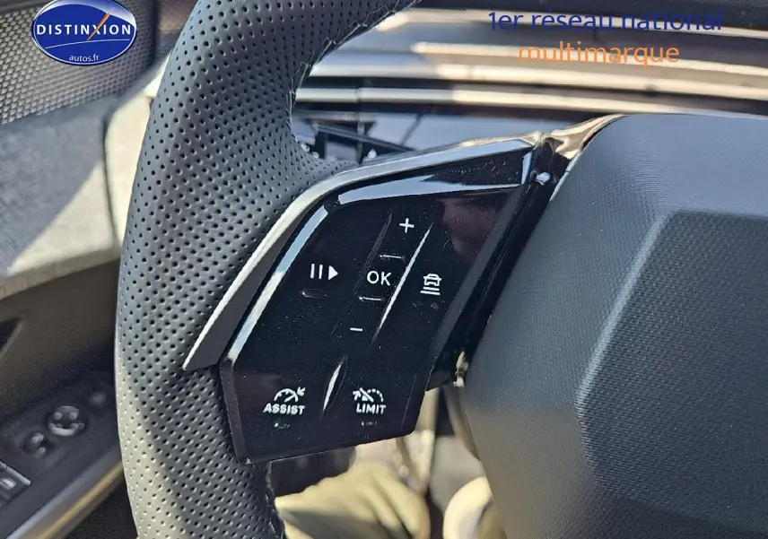 Gros plan sur les commandes au volant cuir perforé côté gauche du Peugeot 3008 noir hybride 2025.
