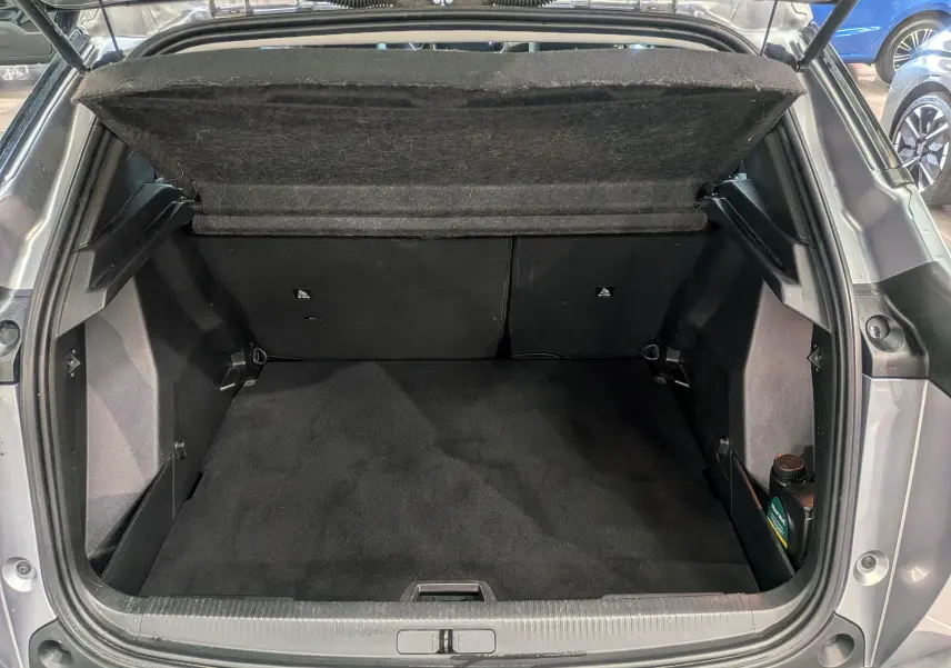 Coffre ouvert vu de l'arrière d'un Peugeot 2008 Gris Artense, montrant un espace de chargement propre et vide.