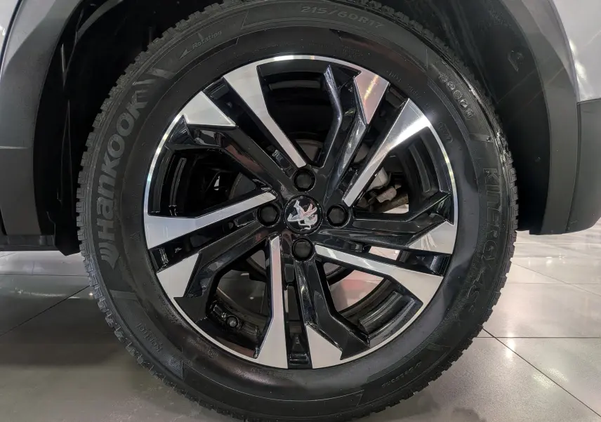 Gros plan sur la roue avant droite du Peugeot 2008 gris Artense, jante alliage noire et argentée au design moderne.