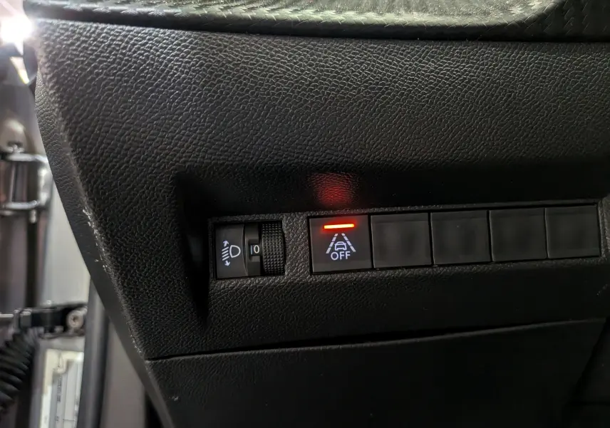 Détail du tableau de bord noir du Peugeot 2008 PureTech 100 Allure 2021 avec bouton d'alerte de maintien de voie désactivé.