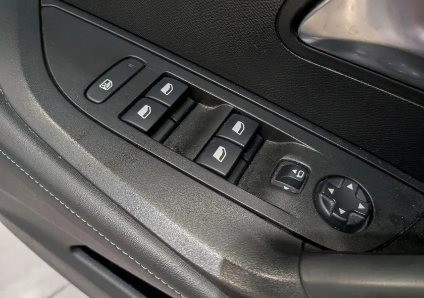 Gros plan sur les commandes de lève-vitres et réglage des rétroviseurs côté conducteur d’un Peugeot 2008 Gris Artense.