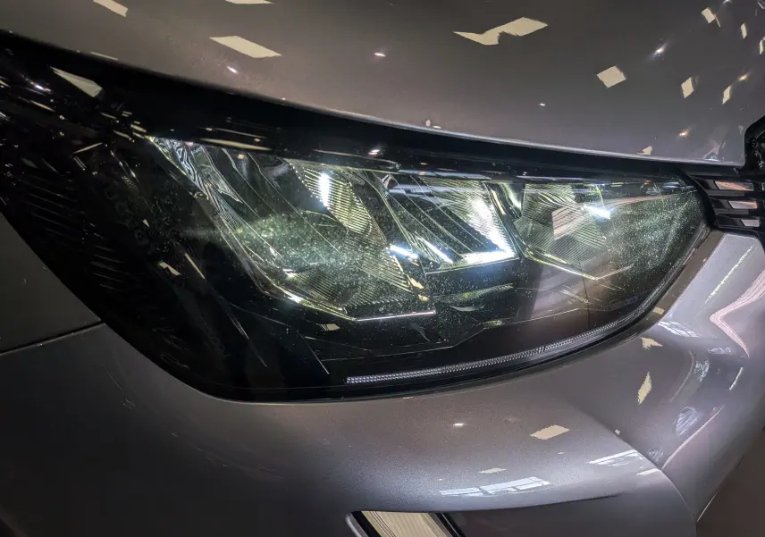 Gros plan sur le phare avant droit gris Artense du Peugeot 2008 PureTech 100 Allure 2021, détails lumineux visibles.