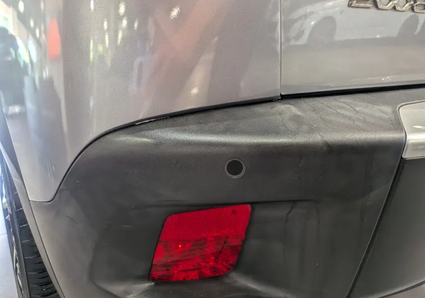 Détail du pare-chocs arrière droit gris Artense d’une Peugeot 2008 avec feu antibrouillard et capteur de recul.