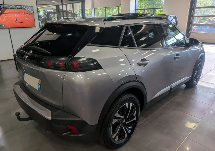 Peugeot 2008 gris Artense vue 3/4 arrière droit en intérieur, avec toit noir et jantes bi-ton distinctives.
