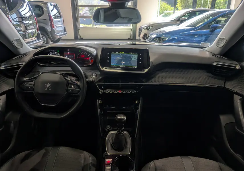 Vue intérieure frontale du tableau de bord du Peugeot 2008 gris Artense avec écran tactile et volant compact multifonction.