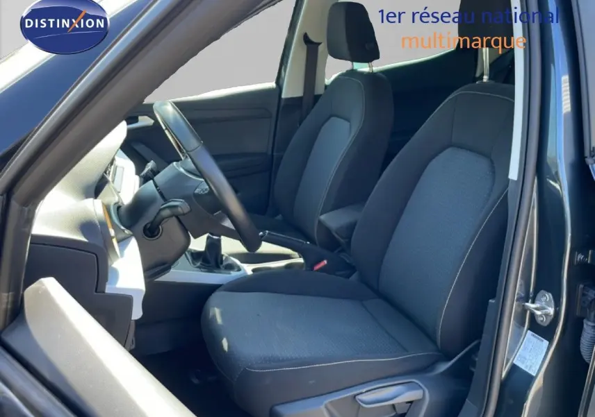 Vue intérieure côté conducteur du SEAT Arona gris Magnetic Metal, montrant les sièges tissu gris et la console centrale.