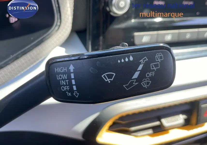 Gros plan sur la commande d’essuie-glace dans l’habitacle gris noir du SEAT Arona 2025, toit noir visible en arrière-plan.