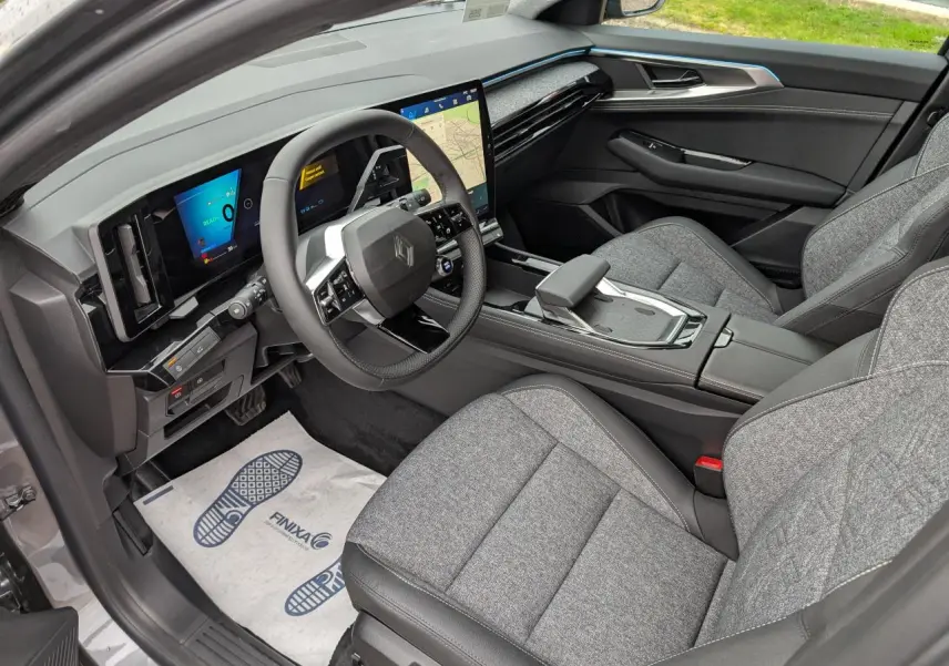 Vue intérieure côté conducteur du Renault Austral gris, avec tableau de bord numérique et sellerie tissu gris clair.